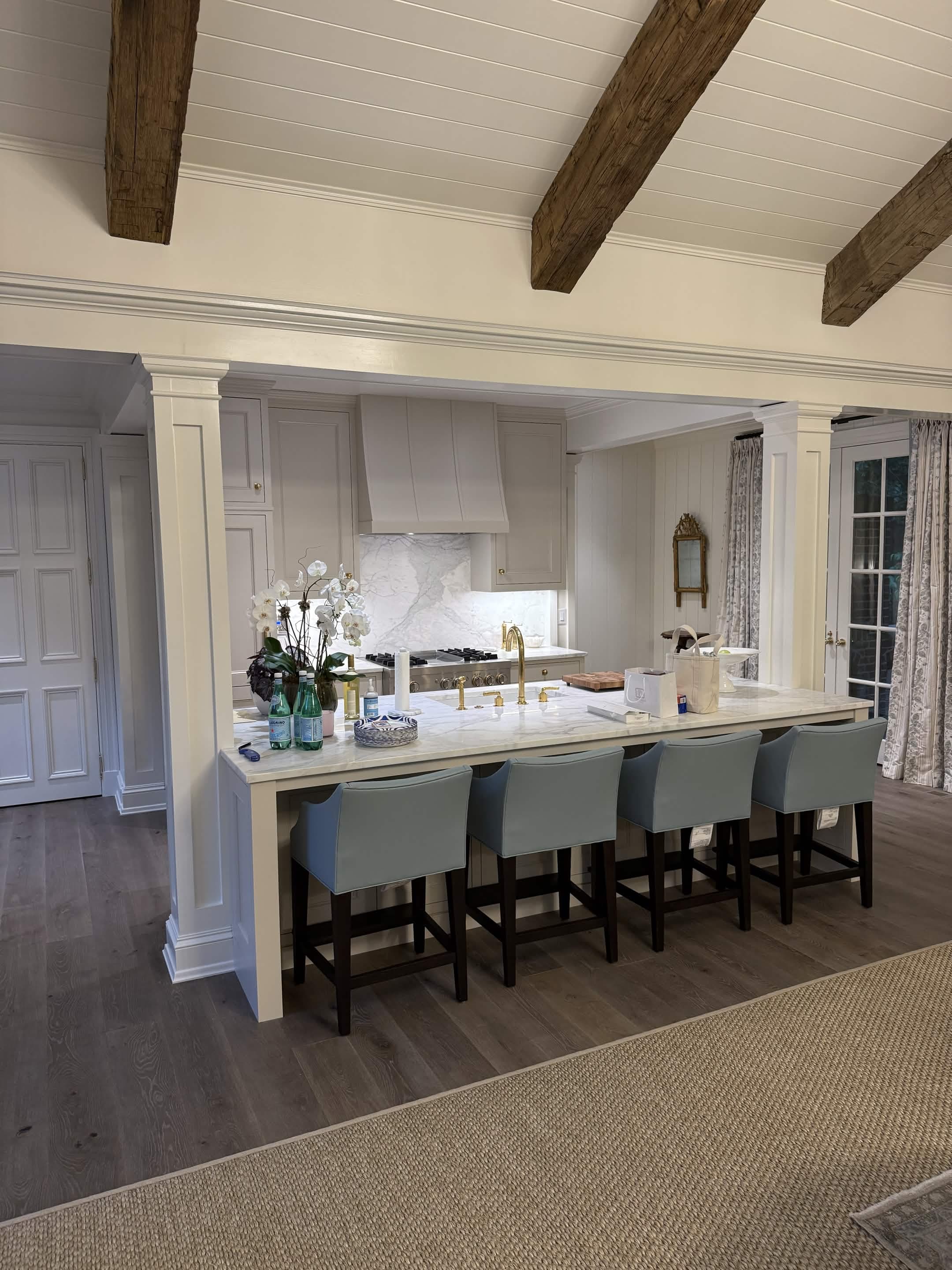 A chef's kitchen with a marble island, custom range hood, and brass fixtures