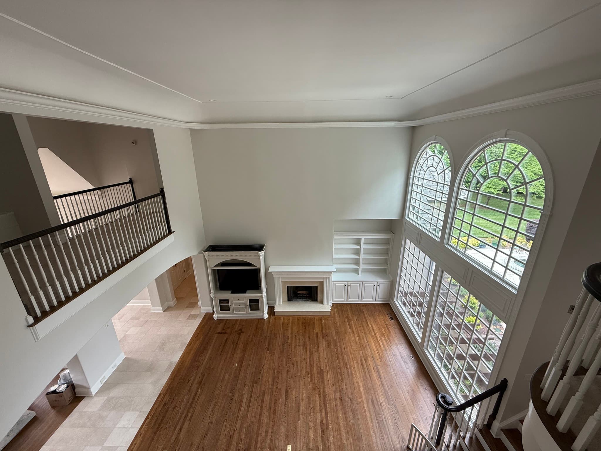 A double-height great room with arched windows and a stone fireplace