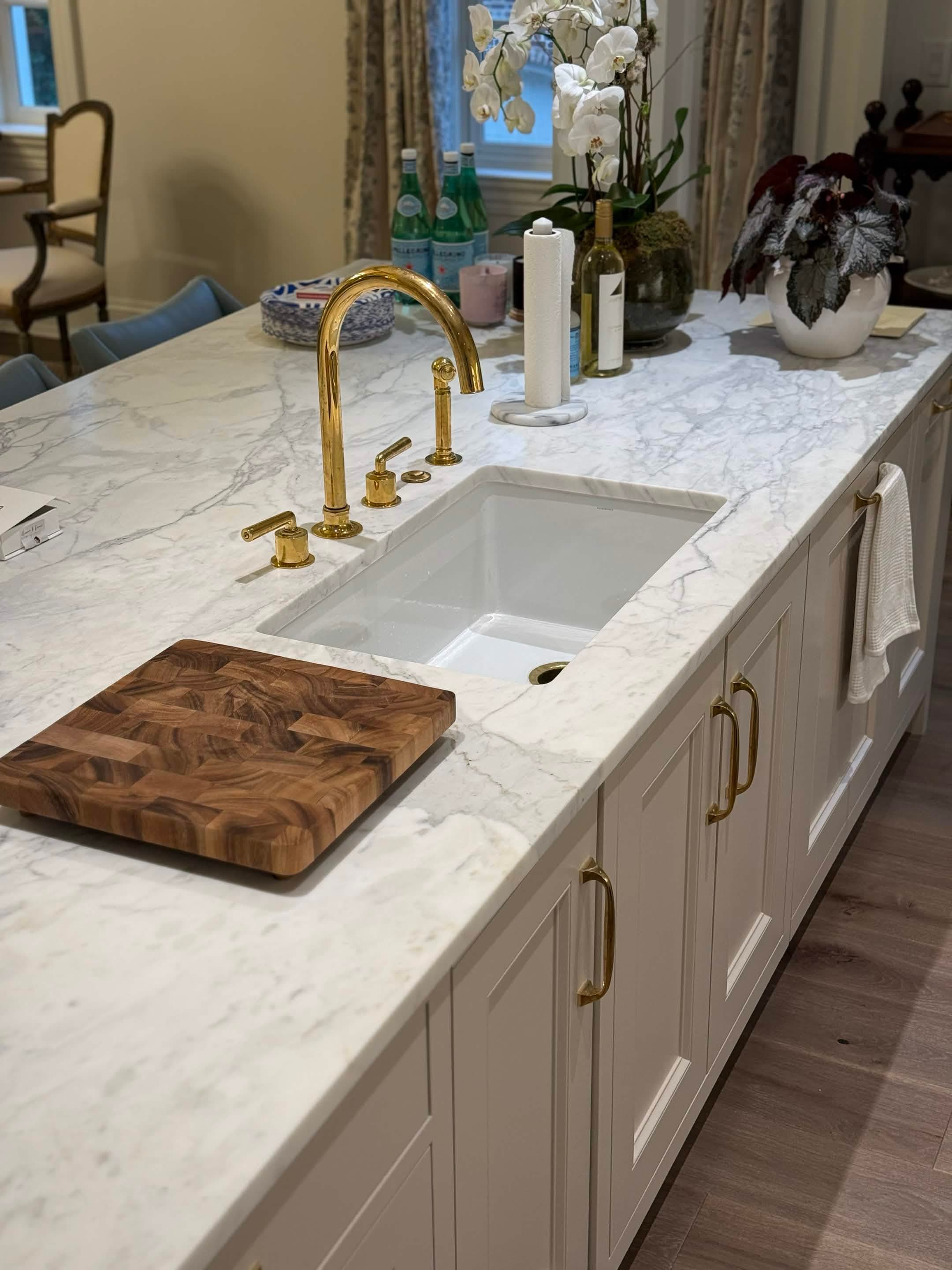 A marble island detail with an unlacquered brass faucet and a fluted apron sink