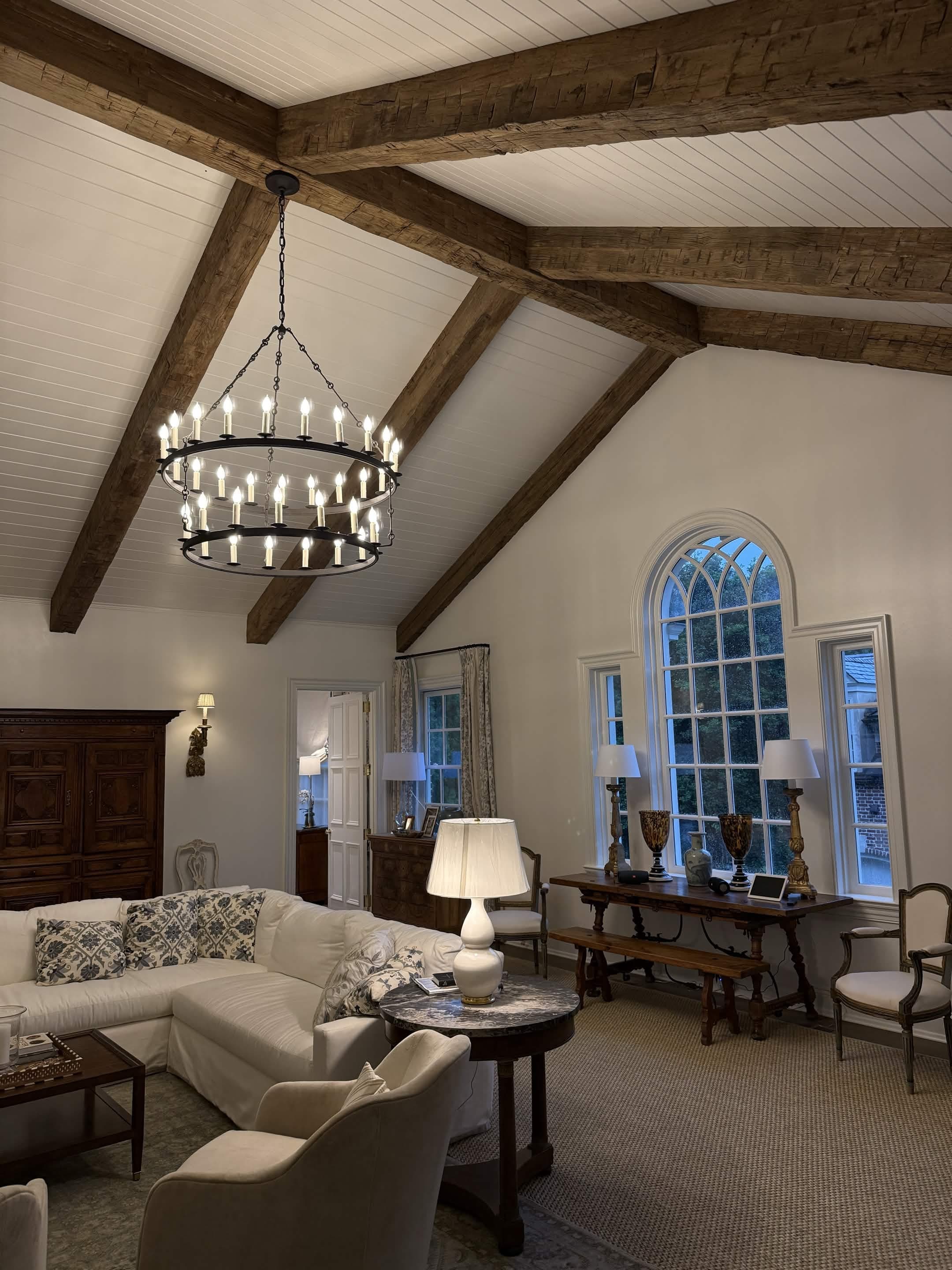 A vaulted great room with a two-tier candle chandelier and a Gothic arched window