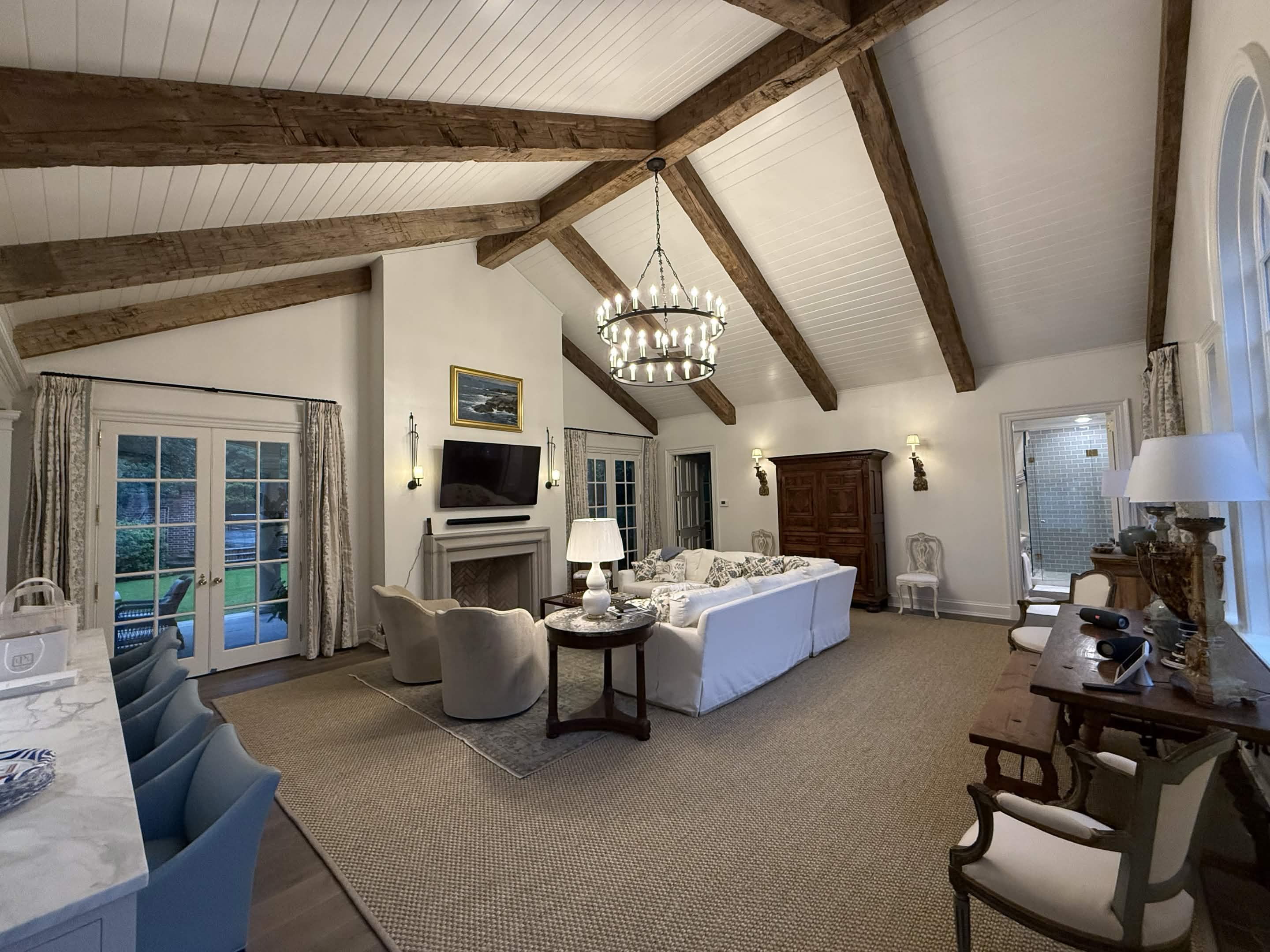 An owner's retreat with vaulted timber beams, a limestone fireplace, and French doors to the garden